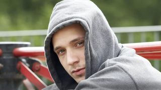Ein Jugendlicher im grauen Hoodie schaut in die Kamera.