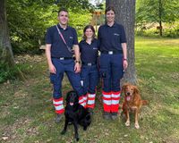 Abgebildet sind drei Personen in Einsatzbekleiung des Malteser Hilfsdienst sowie zwei Hunde, die die Prüfung als Kadaverspürhunde erfolgreich abgelegt haben.