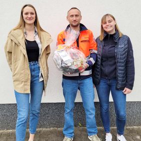 Zwei Frauen bedanken sich mit einem Präsentkorb bei einem Ausbilder des Lehrgangs für Rettungssanitäter