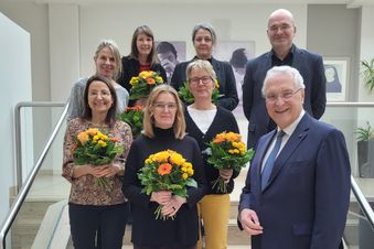 Gruppenfoto auf einer Treppe mehrere Personen halten Blumensträuße ein Mann steht vorn im Anzug.