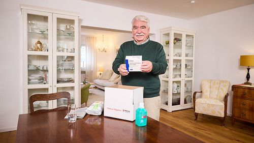 Senior packt die Malteser Pflegebox aus.