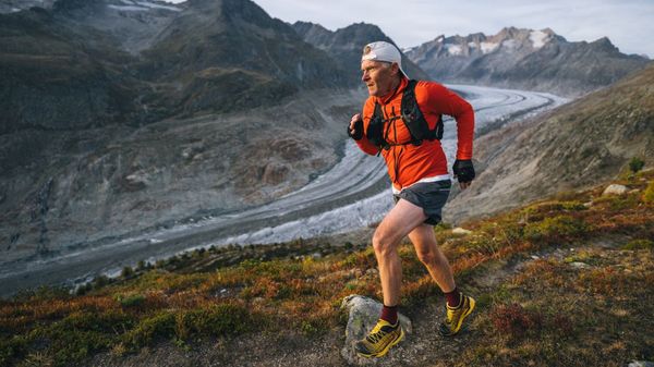 Ein älterer Mann in Laufkleidung bei einem Trailrun vor Bergkulisse