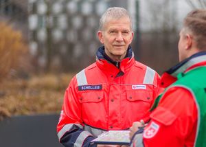 Ein Mann in seinen 60ern steht in Einsatzkleidung im Freien. 