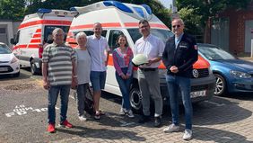 Eine Gruppe von Menschen steht vor einem Krankentransportwagen.