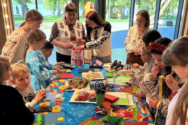 Ukrainische Kinder basteln an einem Tisch. 