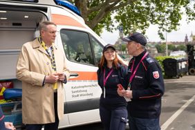 Drei Personen am Herzenswunsch-Krankenwagen im Austausch. 