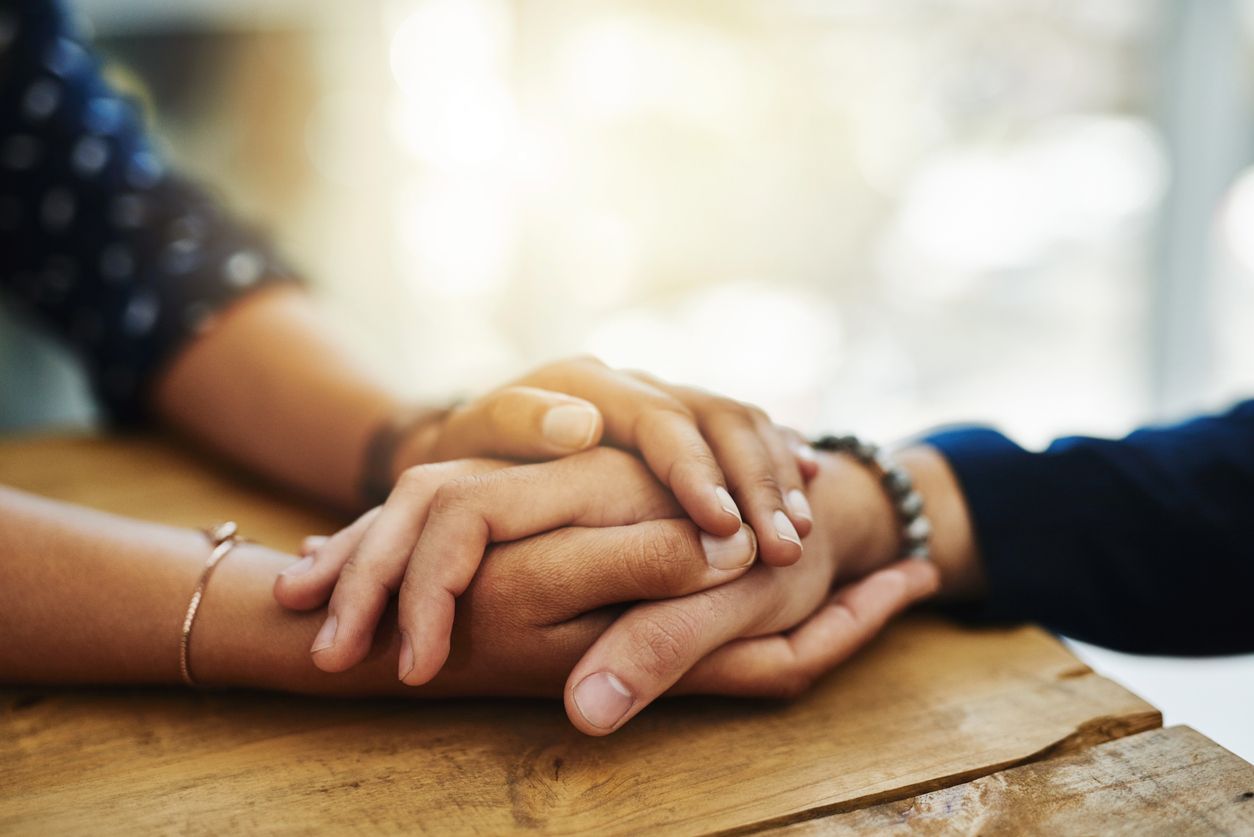 Die Hand eines jungen Mannes in den Händen einer jungen Frau.