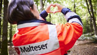 Malter Helferin formt mit den Händen ein Herz