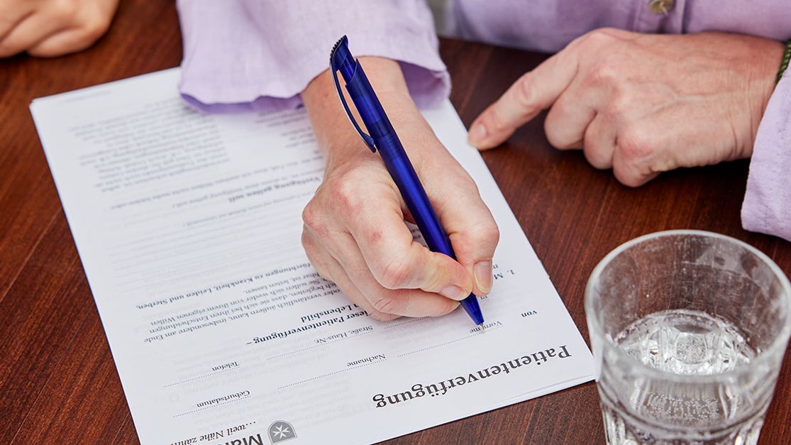 Malteser Patientenverfügung: Nahaufnahme einer Hand mit Stift in der Hand