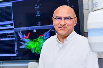 Mann im Arztkittel vor einem Monitor.