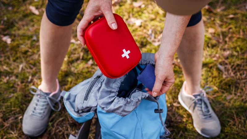 Eine Frau verstaut einen Erste-Hilfe-Kasten in einem Wanderrucksack