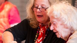 Eine Ehrenamtliche spricht mit einer älteren Dame