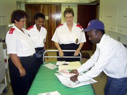 Three nurses and a man stand around a treatment bed.