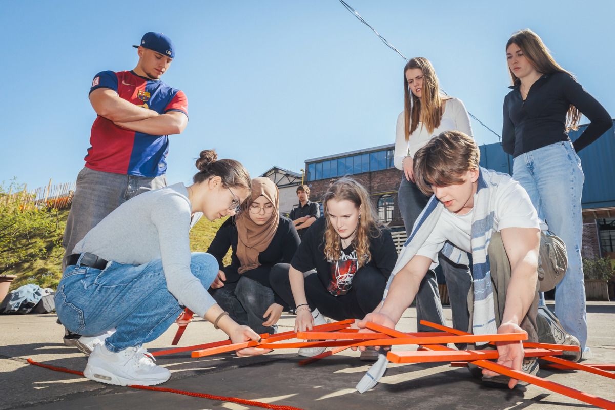 Seminarteilnehmende bei einem Teamspiel mit Stielen im freien