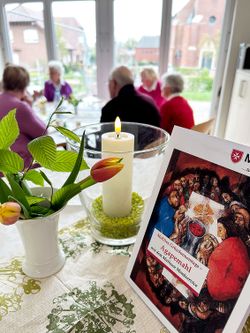 Blumen, Kerze und Malteser-Flyer zum Agape-Mahl