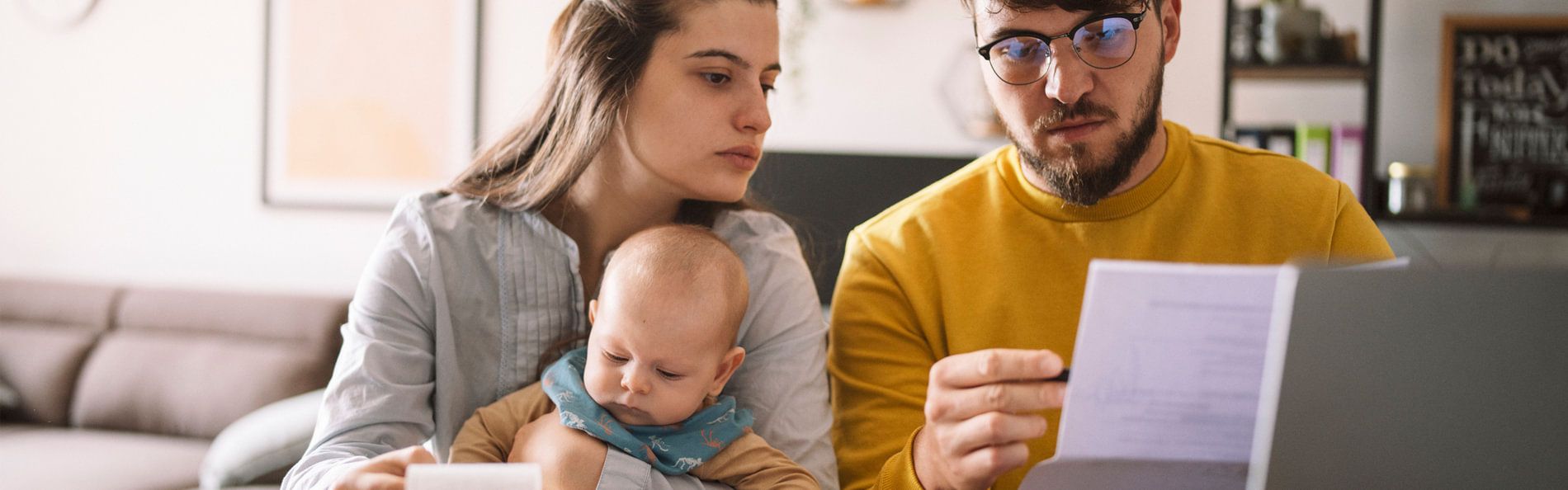 Eine junge Familie vor Rechnungen auf einem Wohnzimmertisch