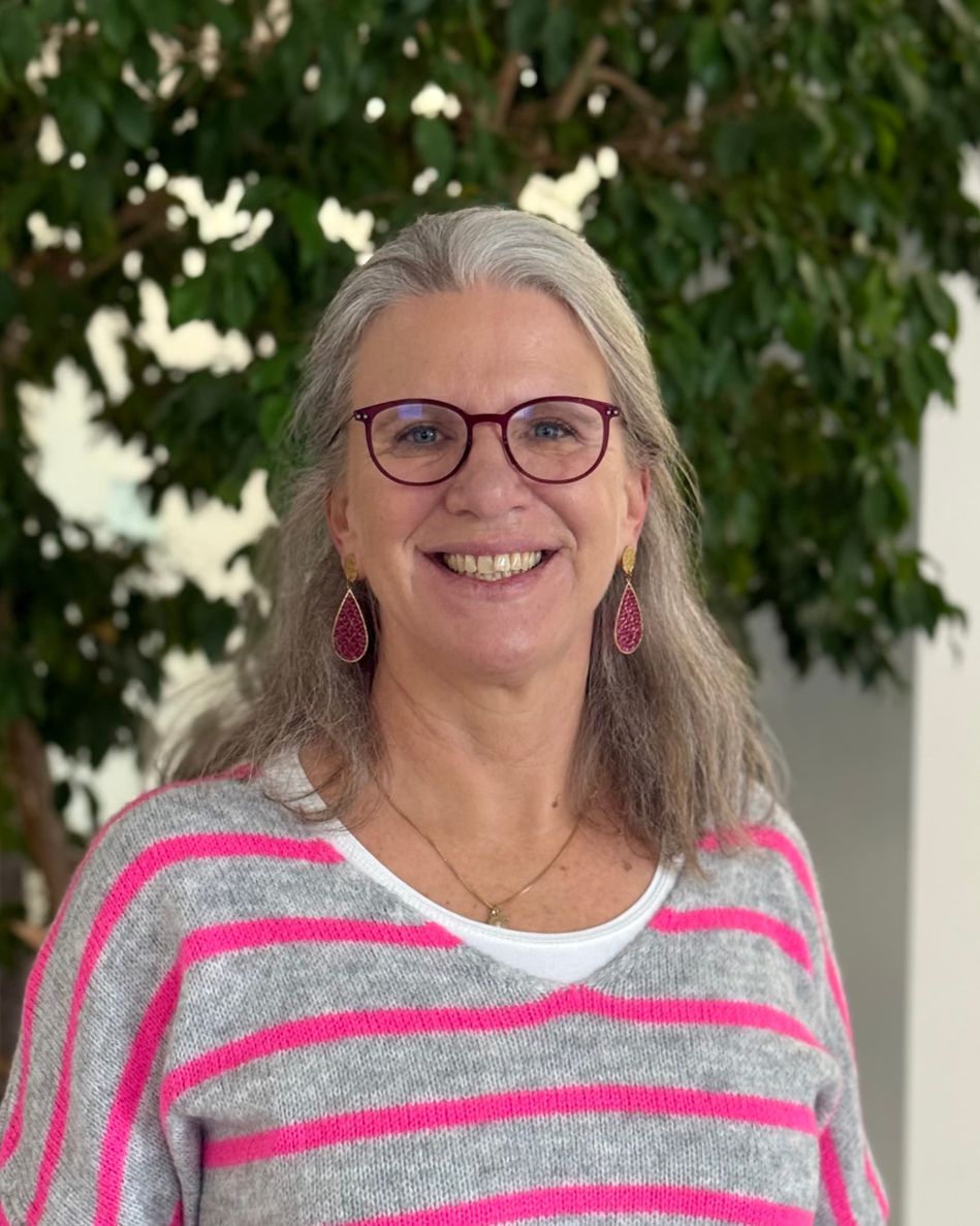 Porträt einer lächelnden Frau mit Brille.