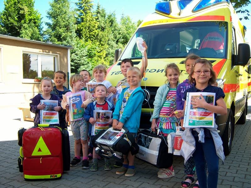 Fröhliche Kinder stehen vor einem Rettungswagen