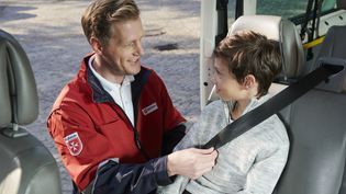 Mitarbeiter kontrolliert ob ein Kind richtig angegurtet ist