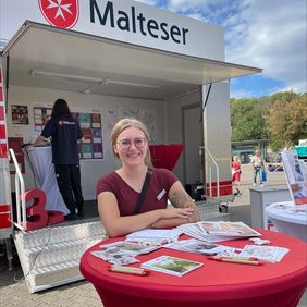 Eine Frau steht an einem Info-Tisch.