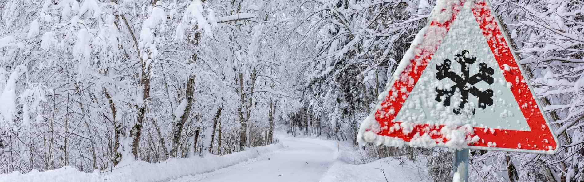 Eine verschneite Straße und das Verkehrsschild „Schneeflocke“.