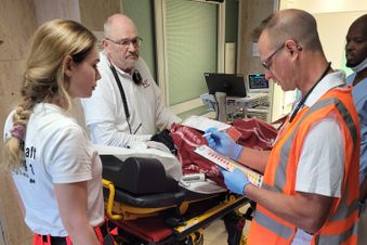Notfallteam übergibt Patientin auf Trage an Klinikpersonal, Übergabeprotokoll wird geprüft.