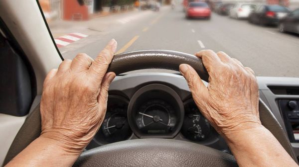 Das Auto-Lenkrad wird von einer älteren Person betätigt.