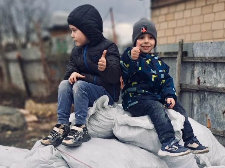 Zwei Junges sitzen auf Säcken mit Sachspenden in der Ukraine