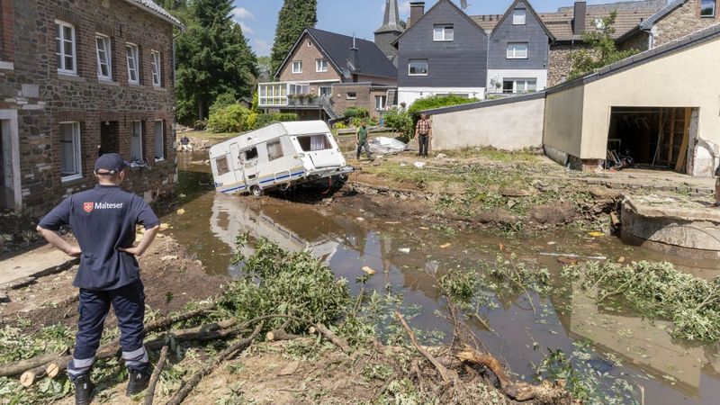Ein Mann mit in die Hüften gestemmten Armen vor einer überschwemmten Straße 