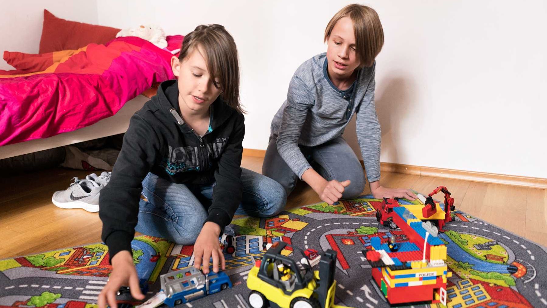 Kinder spielen in einem Kinderzimmer mit Autos