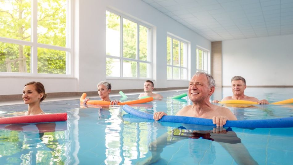 Ältere Menschen bei einer Wassergymnastik mit Pool-Nudeln.