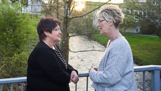 Trauerbegleitung: Zwei Frauen stehen auf einer Brücke und unterhalten sich. 