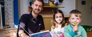 Ein Malteser Helfer, zwei Kinder, Bücher und Stifte