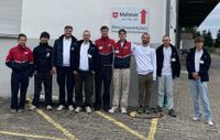 Ein Team junger Menschen in Malteser-Kleidung steht vor einem weißen Gebäude