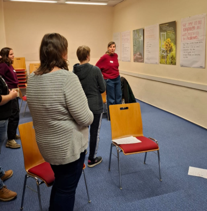 Eine Gruppe von Menschen steht vor Postern und Flipcharts zu den verschiedenen Themen, die im "Treffpunkt Arbeit" besprochen wurden.