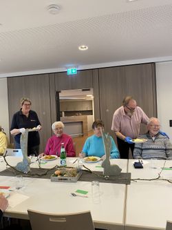 Malteser Helfer servieren den Gästen die Hauptmahlzeit an einem dekorierten Tisch