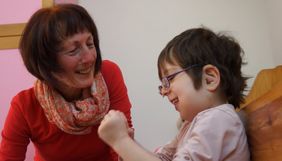 Schwer krankes Mädchen lacht mit Mitarbeiterin der Malteser