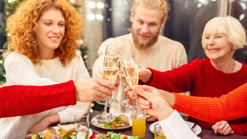 Eine Gruppe Menschen stößt an einem Tisch mit Sektgläsern an