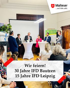 Mehrere Personen nehmen an einer Podiumsdiskussion in einem Veranstaltungsraum teil, während ein Publikum aufmerksam zuhört. Im Hintergrund sind eine Leinwand und ein Banner des Integrationsfachdienstes sowie ein Malteser-Logo sichtbar.