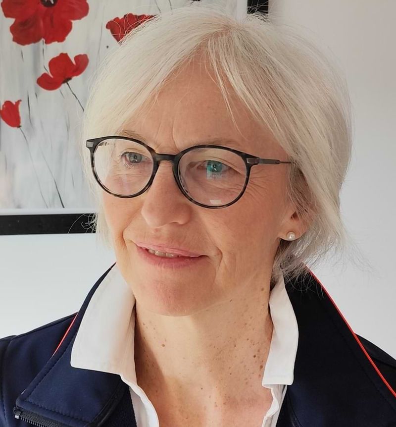 Porträt einer lächelnden, älteren Frau mit Brille.
