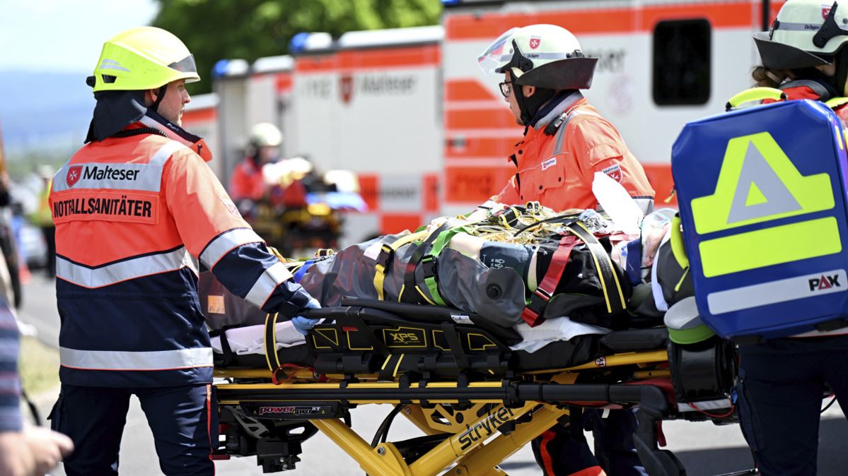 Drei Notfallsanitäter helfen einer verletzten Person auf einer Liege.