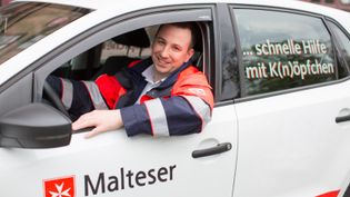 Ein Auto mit Malteser Logo und Fahrer