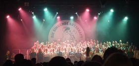 Das Foto zeigt den Chor "Die Singende Botschaft" auf der Bühne bei seinem Weihnachtskonzert am 18.12.2025