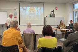 Menschen lauschen der Ukrainerin vor einer Präsentation in einem Raum