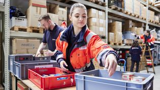 Frau mit Packkiste vor Regal