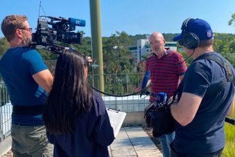 Kamerateam mit drei Personen filmt und interviewt einen Mann.