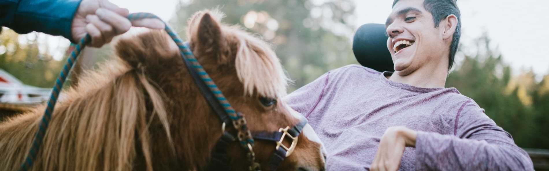 Ein Mann im Rollstuhl mit einem kleinen Pony.
