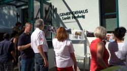 Menschen stehen vor dem Gemeindehaus Sankt Hedwig in Görlitz beisammen und reden.