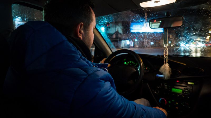 Junger Mann sitzt in Bus und fährt nachts.
