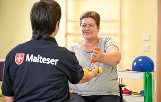 Pflegerin und Patientin bei einer Übung mit einer Hantel